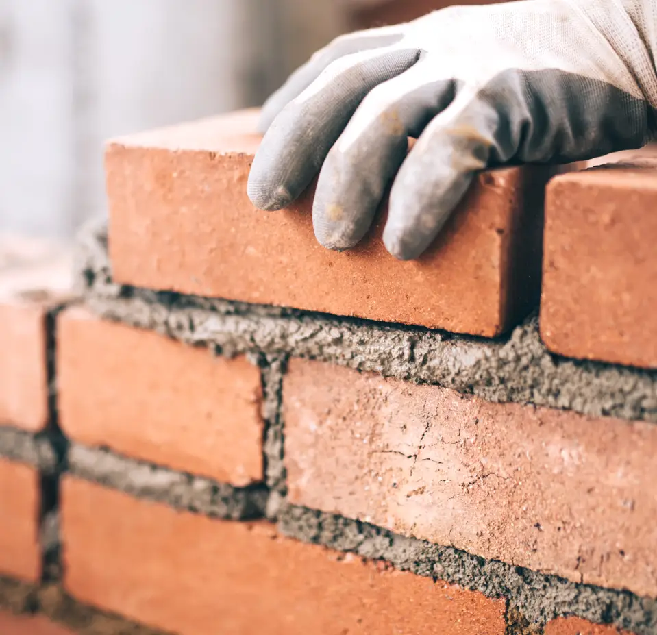 mans hand on bricks building chimney