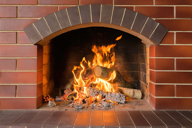 Hansen And Sons - stock photo of firebox Lit fireplace with brick surround