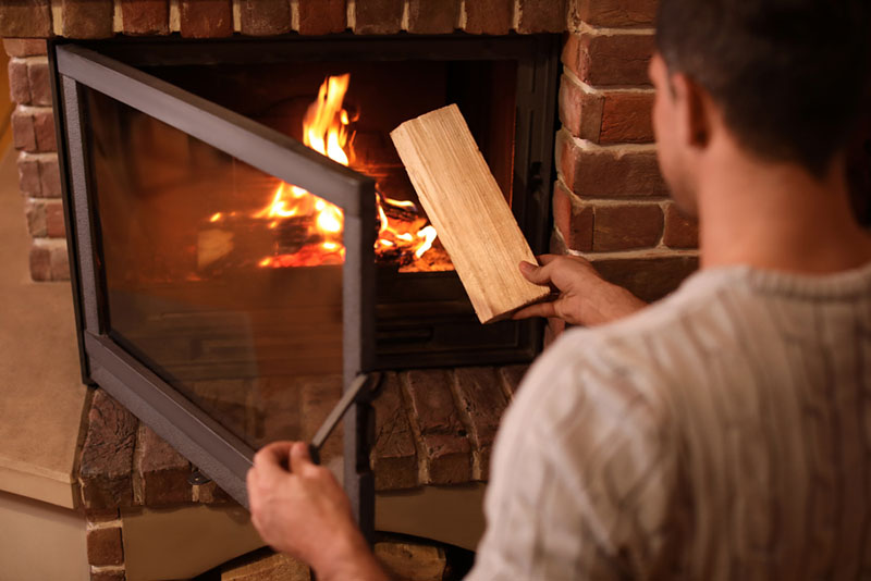 Man putting firewood into fireplace