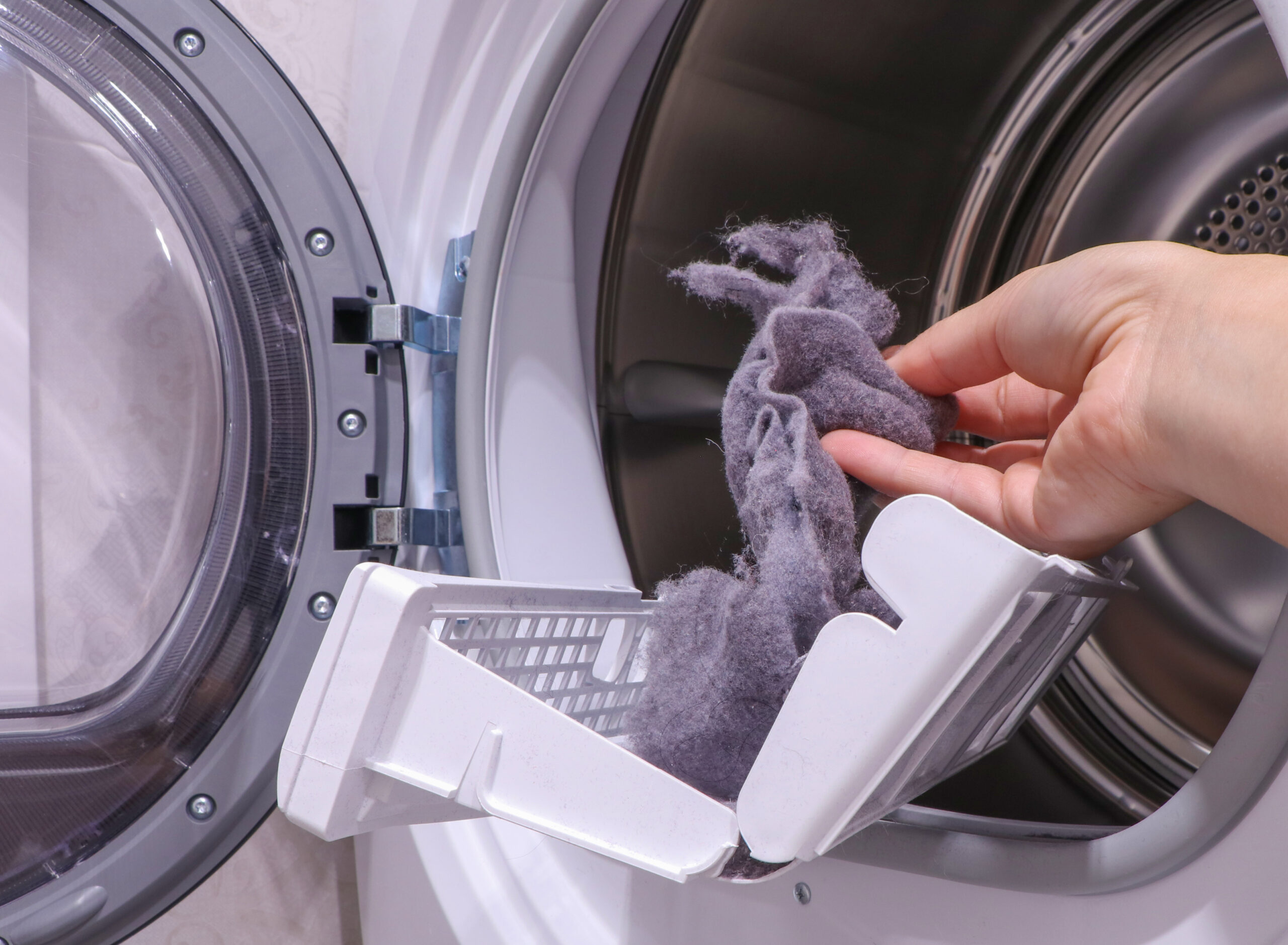 Adobe Stock image of someone pulling dryer lint from their dryer vent trap.